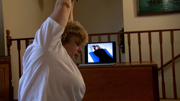 Diane Oerly practicing yoga at home with an instructional video by Lynn Rossy. University of Missouri Cooperative Media Group