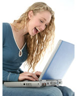 Woman laughing and typing on laptop