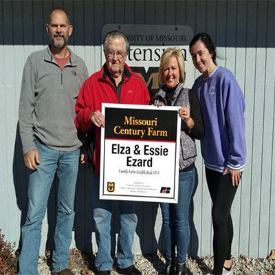Elza Ezard and members of this family hodling a century farm sign.