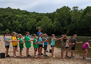Campers and Camp Counselor doing activity on rocky beach at the lake