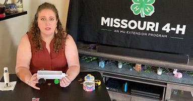 Chelsea Corkins, 4-H county engagement specialist, discussing potential and kinetic energies as she demonstrates how to make a rubber band car
