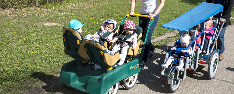 Children in multi-seat strollers out for a walk