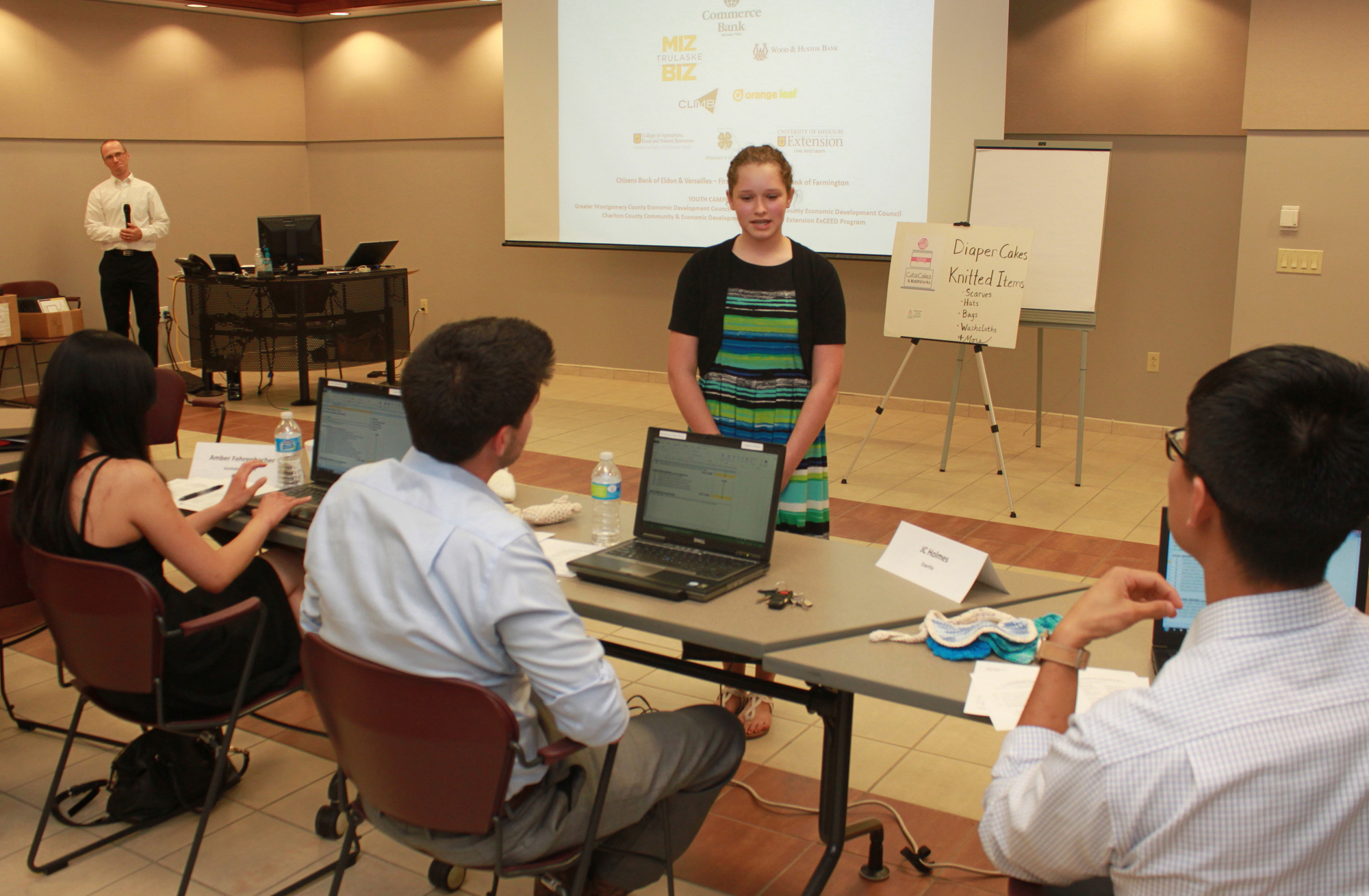 Rebekah Kempker, standing, explains her business concept to a panel of judges at the closing session of 4-H Build-A-Business camp. The session offered campers a forum for pitching their entrepreneurial ideas to actual business owners.