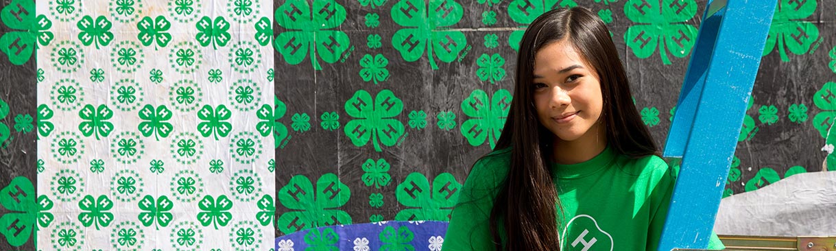 A young woman posing in front of a 4-H wall