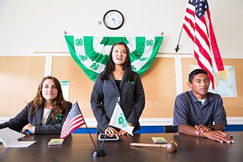 4-H club members sit at a table during a meeting.
