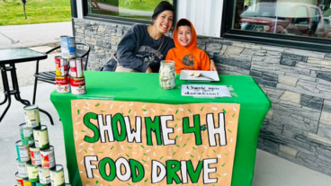 adult and child at a food drive booth