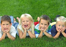 Four happy kids lying on the grass.