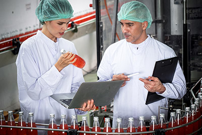 Employees checking bottled drinks in manufacturing plant