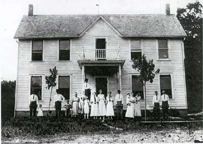 Old photo of farmhouse with inhabitants standing outside