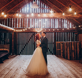 A couple posing in a barn for wedding photos