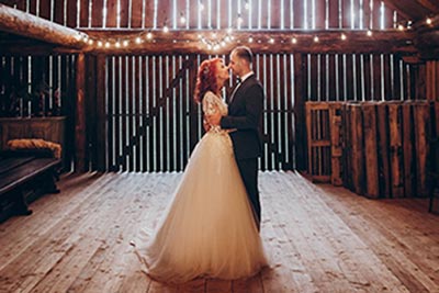 A couple posing in a barn for a wedding photo.