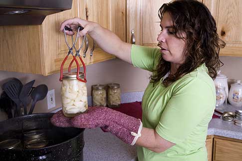 Woman taking jar from canner