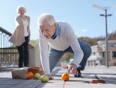man bending to pick up fruit spilled after a fall