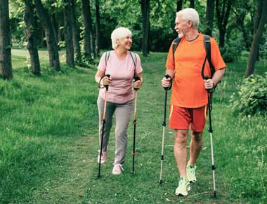 Senior couple walking in woods using walking sticks