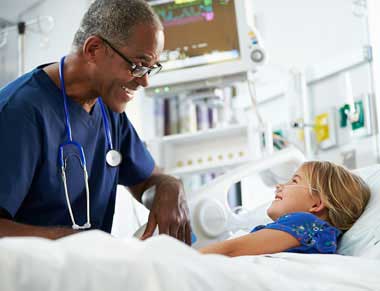 Male nurse talking to child in hospital bed