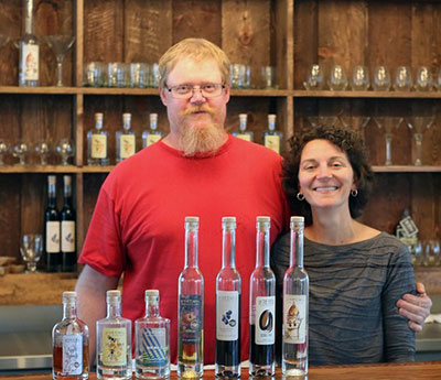 Jim Pierce and Sarah Burnett Pierce pose at the bar in Of the Earth Farm Distillery.