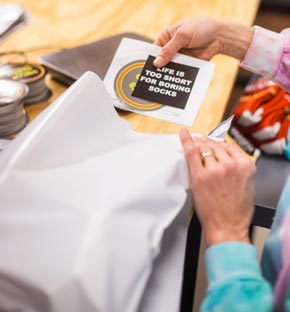 A worker adding branded materials to a package of socks. Image property of Court Street Custom Fulfillment. Used with permission.