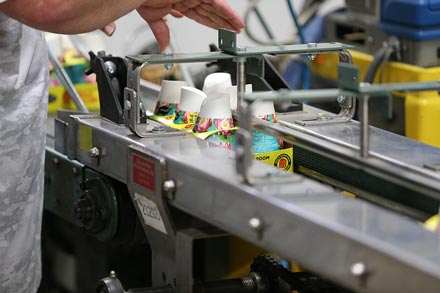 A person's arms and hands above a product packing machine.