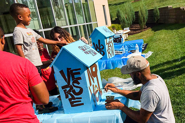 Artist Cbabi Bayoc demonstrating stenciling the community boxes STL Promise Zone boxes.