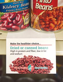 A shelf talker on the canned bean shelf extolling the high protein and fiber, and low fat and sodium in dried or canned beans.