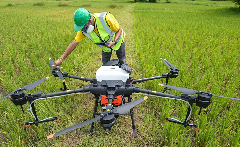 A technician preparing a large agricultural drone equipped to seed cover crops.