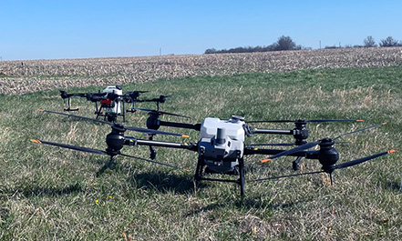 Two T-40 drones equipped with sprayers in a field.