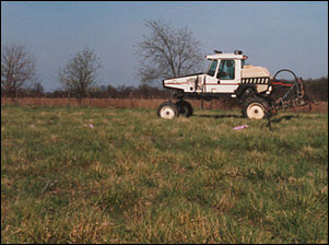 Shows tractor applying herbicides to crops.