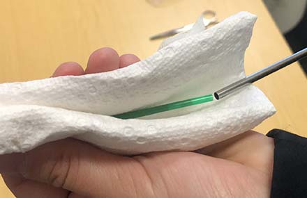 The cotton plug end of a dried straw being inserted into a warmed artificial insemination catheter.
