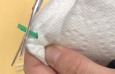 The sealed end of a straw being cut at a 90-degree angle.