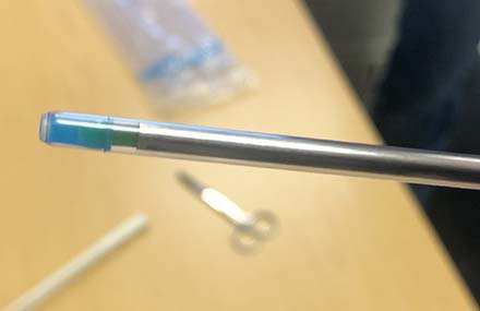 Tip of a plastic sheath locked in place over a straw and catheter.