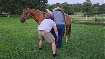A man helping a woman get on a horse.