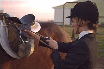 A woman running up the stirrups after dismounting.