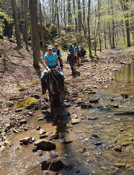 A group riding on a trail by a creek.