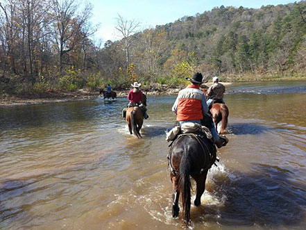 Group on horses crossing a stream.