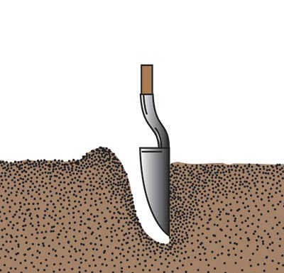 A shovel being stuck into a started hole to make a second cut to straighten the side of the hole opposite the shoveler
