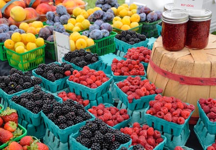 A market produce stand of neatly displayed fruits and berries.