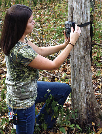 woman placing a camera about waist height on a small tree