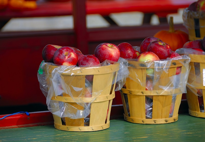 Baskets of apples on a table in a farmers market stall.