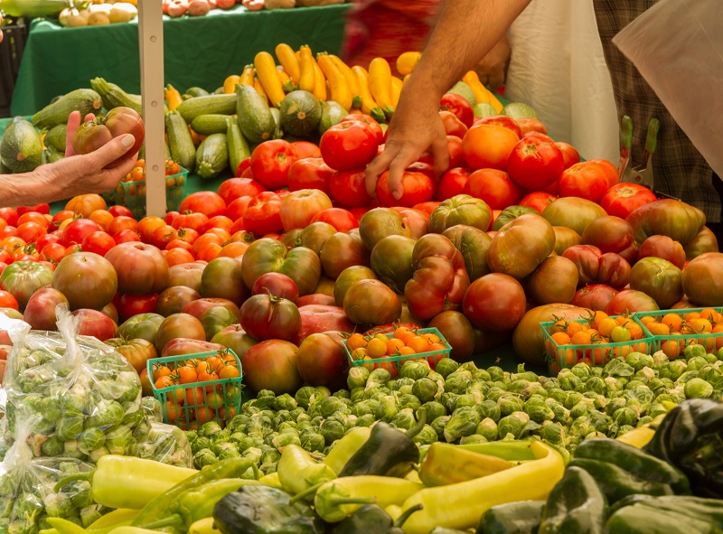 Piles of vegetables on a table in a farmers market stall.