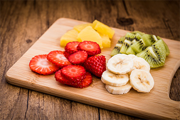 Cutting board with strawberry, banana, kiwi and orange