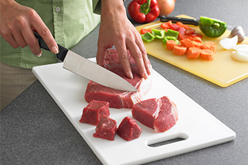 Close-up of man trimming fat off of meat