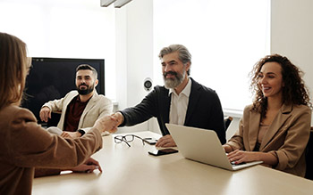 People sitting at conference table talking and shaking hands