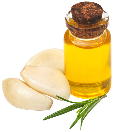 A glass jar of oil with garlic cloves next to it.