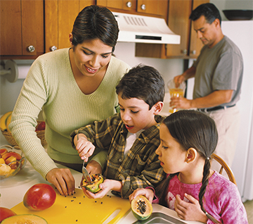 a family cutting fruit in the kitchen together