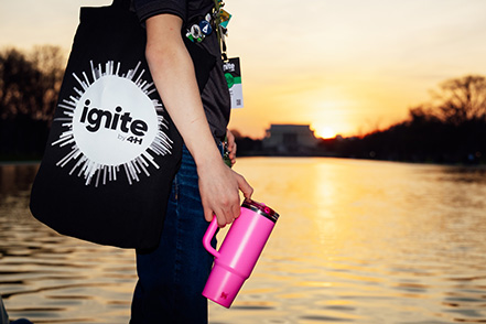 A person standing with an Ignite 4-H bag and water bottle.