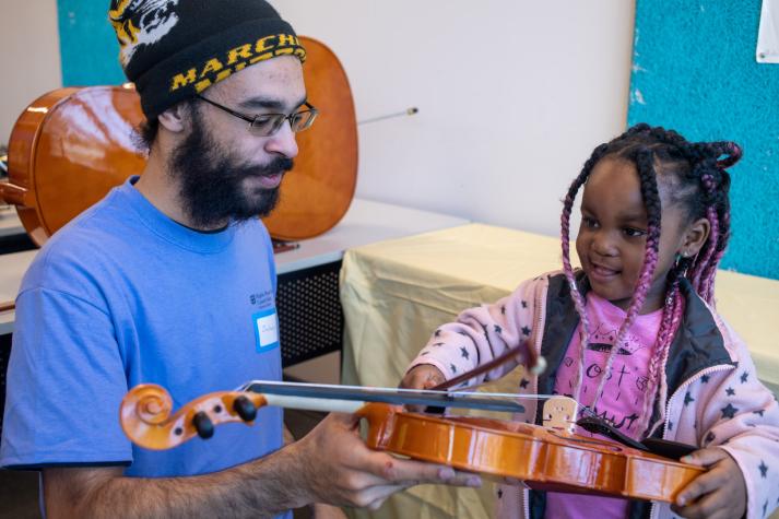 Rian Pargo, right, draws a bow across a violin held by MU student Zachary Davis at the Higday + Mizzou Instrument Petting Zoo, part of the March 7 University of Missouri Science Center Day at the St. Louis Science Center.