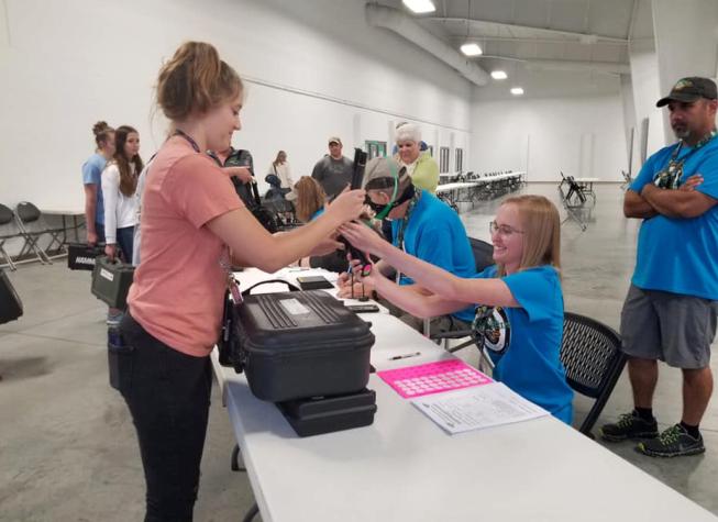 Nichole Gann, seated, volunteers at the 4-H Shooting Sports National Championship in 2019.