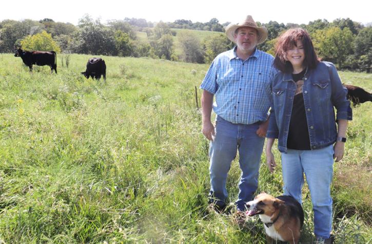 Tad and Kim Carnahan standing in a pasture with a dog.