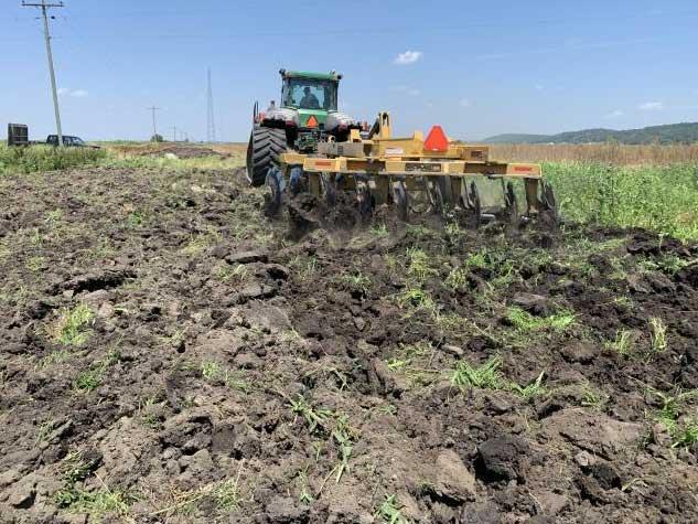 Tractor discing soil.