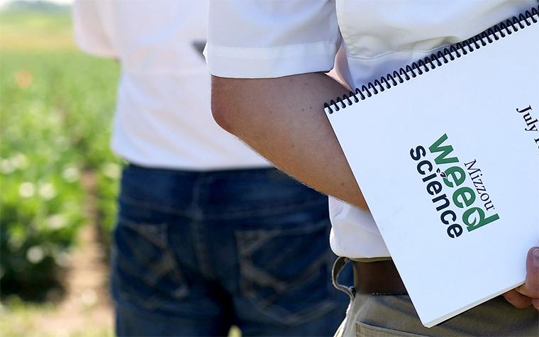 Man holding spiral bound document from MU Weed Science